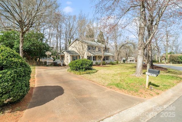 view of front of home with driveway, fence, and a front yard