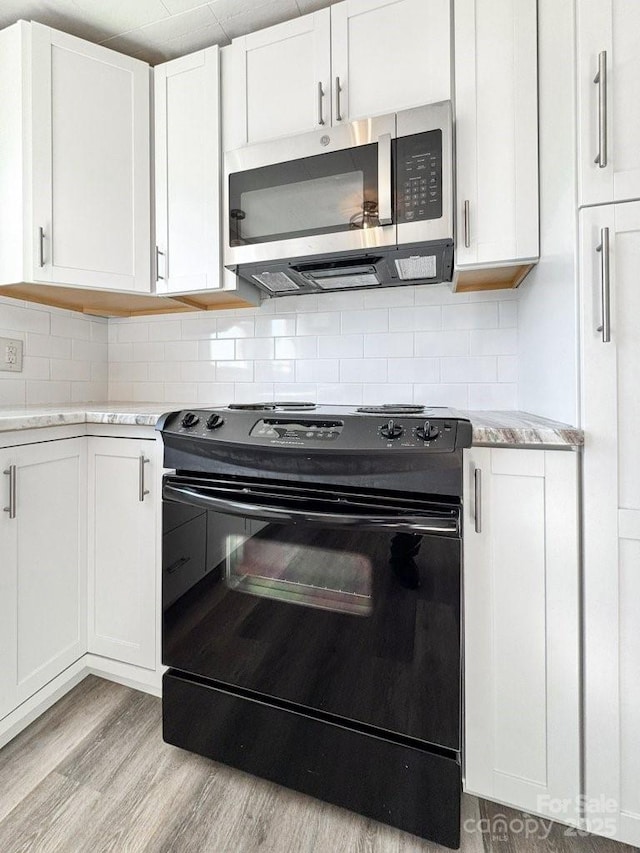 kitchen with white cabinetry, backsplash, black range with electric cooktop, and light hardwood / wood-style flooring