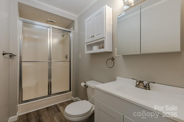 bathroom featuring toilet, walk in shower, hardwood / wood-style floors, crown molding, and vanity