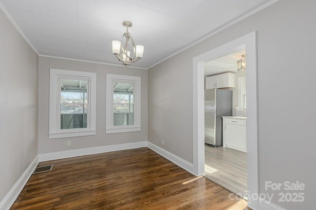 spare room with an inviting chandelier, ornamental molding, and dark hardwood / wood-style flooring