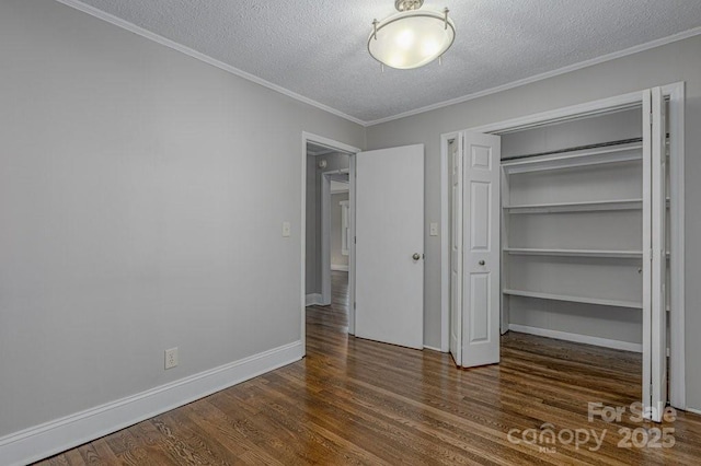 unfurnished bedroom with a textured ceiling, a closet, crown molding, and dark hardwood / wood-style floors