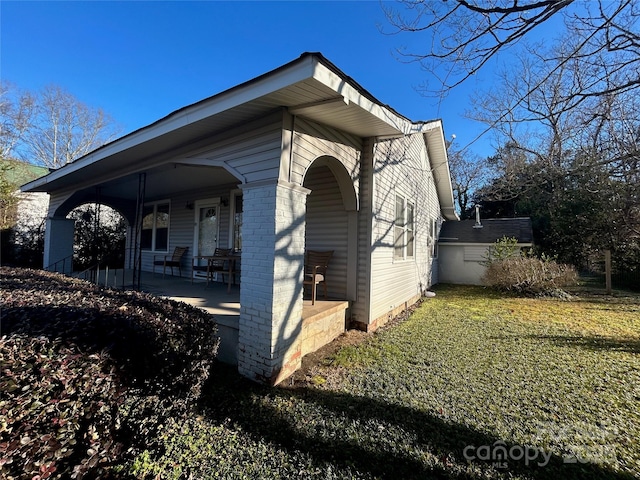 view of property exterior featuring covered porch and a yard