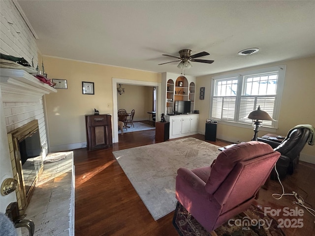 living area featuring visible vents, dark wood finished floors, baseboards, ceiling fan, and a fireplace