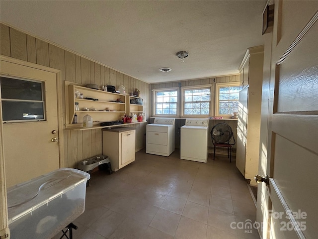 washroom with cabinet space, independent washer and dryer, and wooden walls