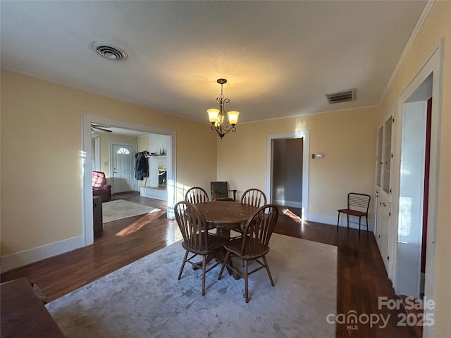 dining room with dark wood-type flooring, a fireplace, and visible vents