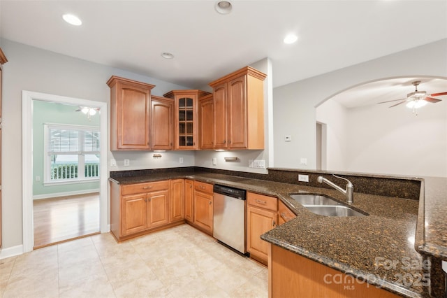 kitchen with ceiling fan, dishwasher, sink, kitchen peninsula, and dark stone counters