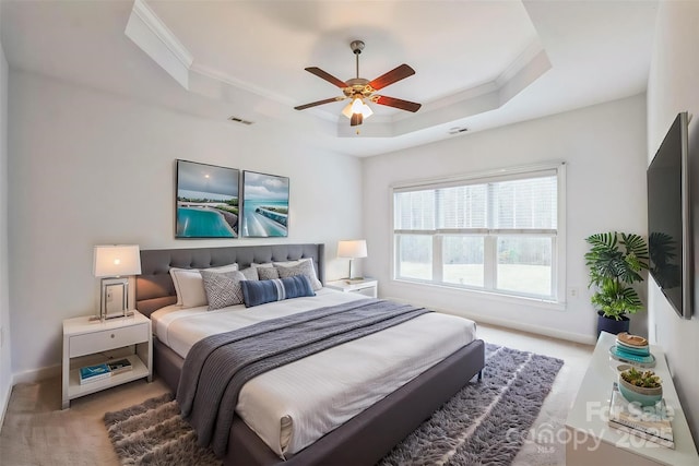 carpeted bedroom with a raised ceiling, ceiling fan, and crown molding