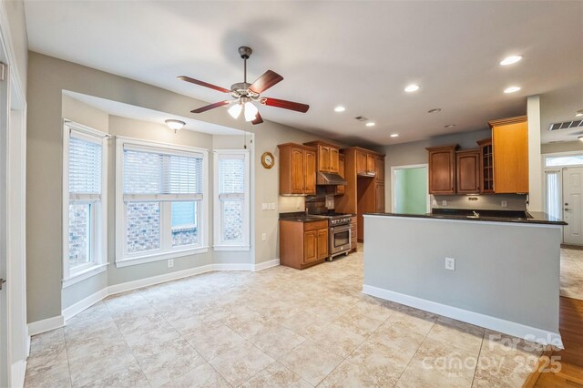 629 Cordova Ct, Salisbury, NC 28146 - kitchen with high end stainless steel range, dark countertops, under cabinet range hood, brown cabinetry, and a ceiling fan