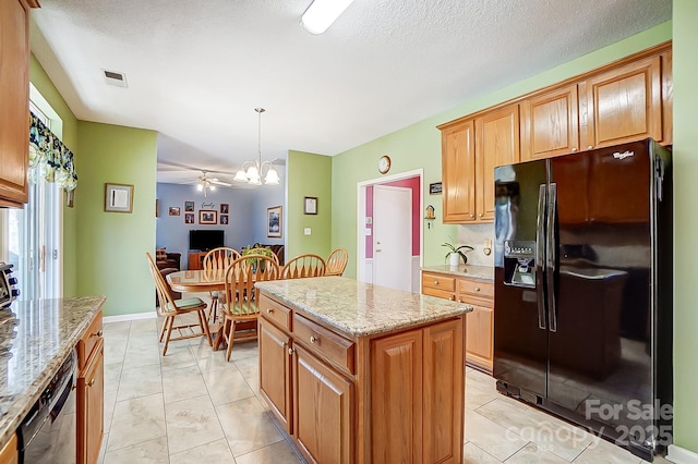 kitchen featuring pendant lighting, light stone countertops, a kitchen island, and black appliances