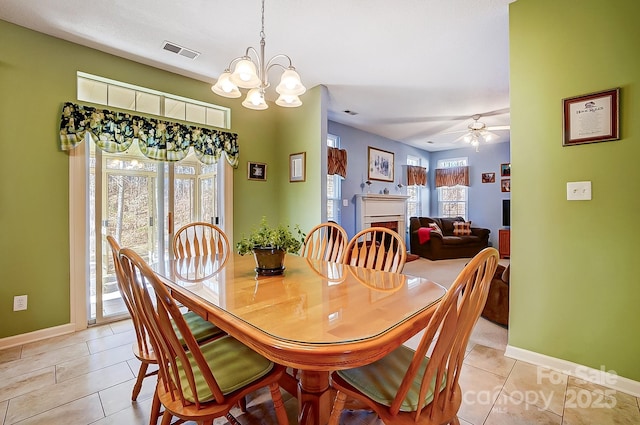 tiled dining room with ceiling fan with notable chandelier