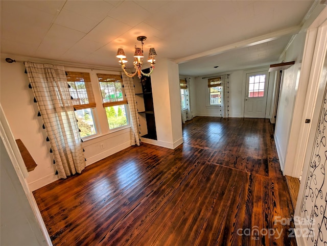 entrance foyer with dark wood-type flooring, ornamental molding, and a chandelier