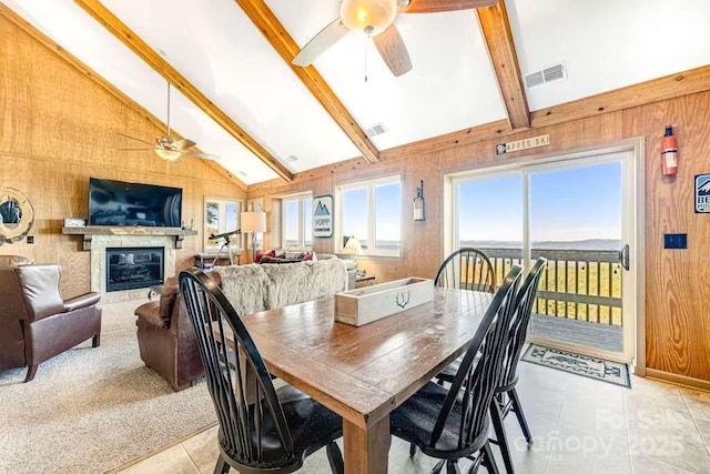 tiled dining room featuring ceiling fan, beamed ceiling, high vaulted ceiling, and wood walls