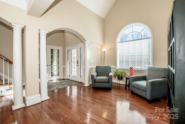 foyer entrance with french doors, vaulted ceiling, decorative columns, and hardwood / wood-style flooring