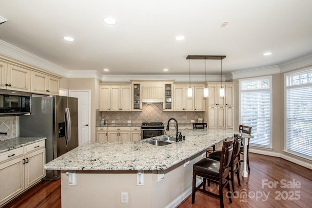 kitchen with stainless steel appliances, a breakfast bar area, hanging light fixtures, and cream cabinetry