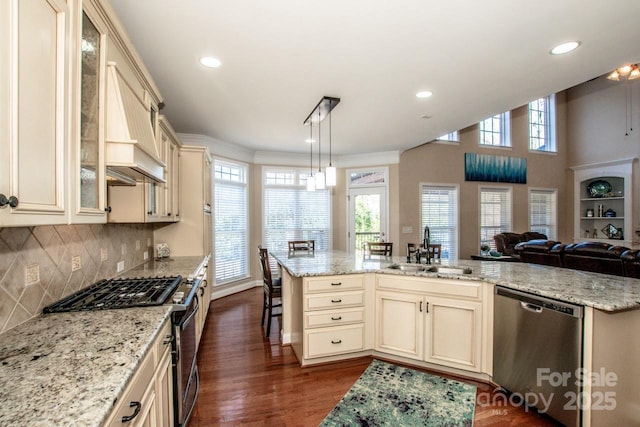 kitchen featuring decorative light fixtures, stainless steel appliances, cream cabinets, and sink