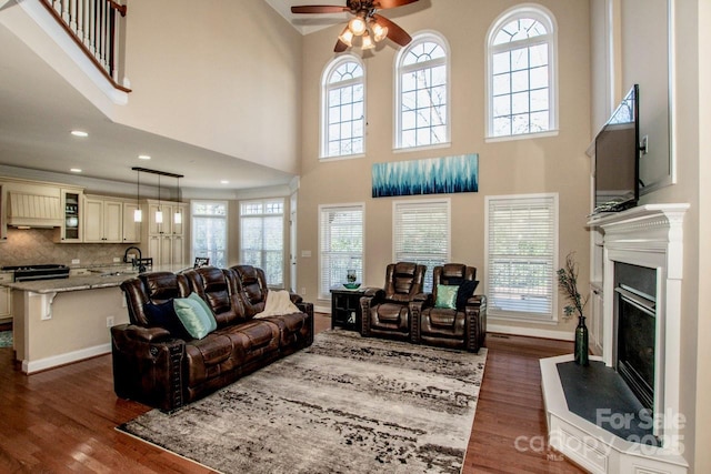 living room featuring a high ceiling, ceiling fan, and dark hardwood / wood-style floors