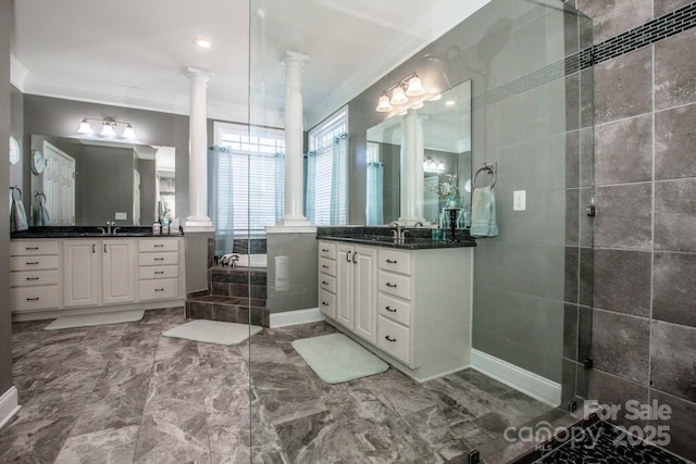 bathroom featuring vanity, crown molding, tiled tub, and ornate columns