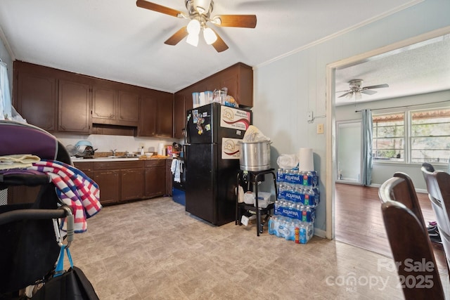 kitchen with sink, ceiling fan, black refrigerator, dark brown cabinets, and ornamental molding