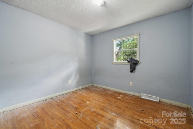 unfurnished room featuring wood-type flooring and a textured ceiling