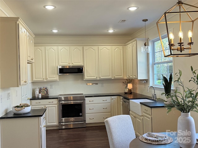 kitchen featuring dark wood-type flooring, sink, tasteful backsplash, hanging light fixtures, and appliances with stainless steel finishes