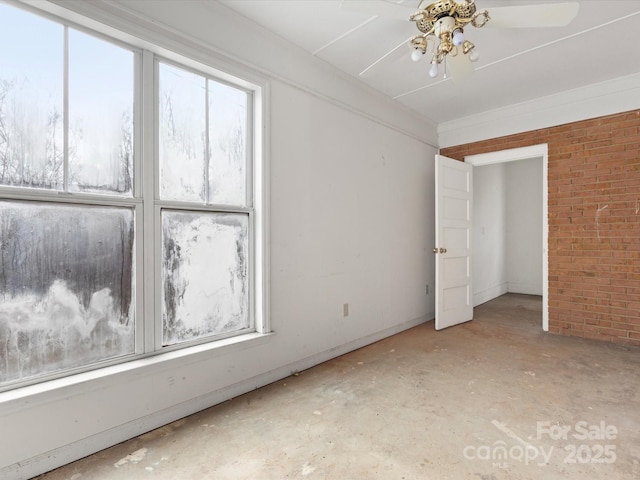 spare room featuring ceiling fan and brick wall