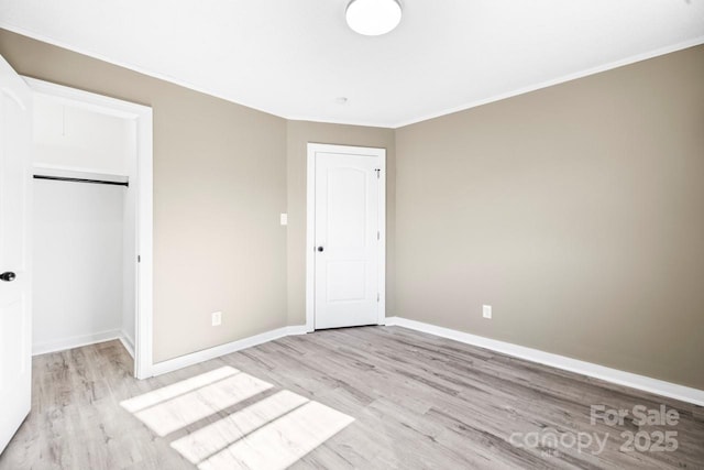 unfurnished bedroom with a closet, light hardwood / wood-style floors, and crown molding