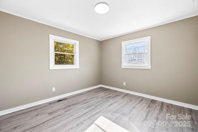 empty room featuring light wood-type flooring and ornamental molding