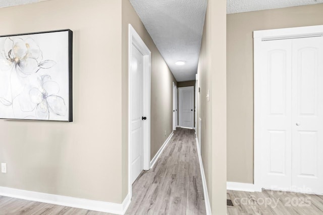 corridor featuring a textured ceiling and light wood-type flooring