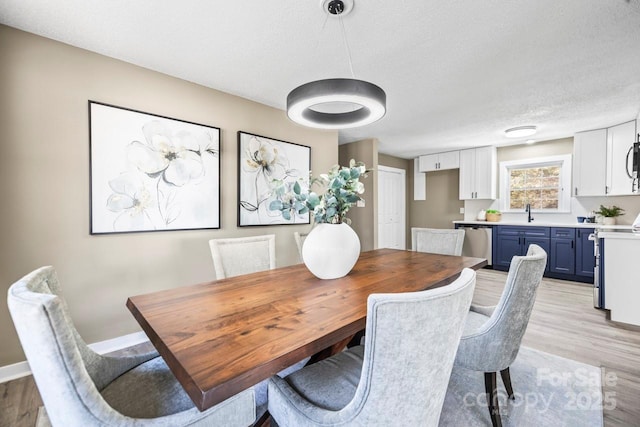 dining space with sink, a textured ceiling, and light hardwood / wood-style floors