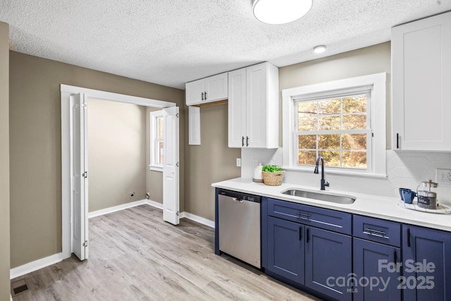 kitchen with stainless steel dishwasher, decorative backsplash, white cabinetry, blue cabinets, and sink