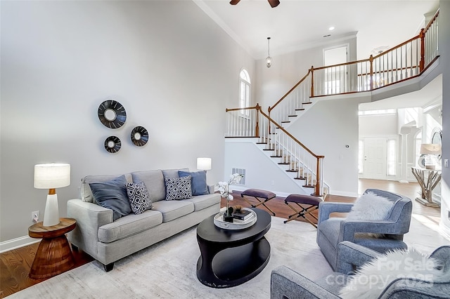 living room with ceiling fan, a towering ceiling, and light hardwood / wood-style flooring