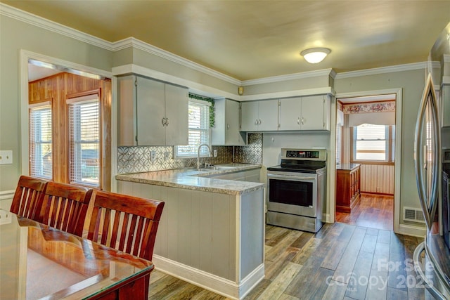 kitchen featuring kitchen peninsula, a healthy amount of sunlight, wood-type flooring, and appliances with stainless steel finishes