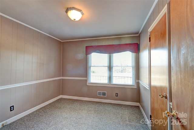 carpeted spare room featuring crown molding and wood walls