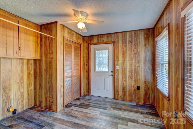 entrance foyer featuring hardwood / wood-style floors, a textured ceiling, ceiling fan, and wood walls