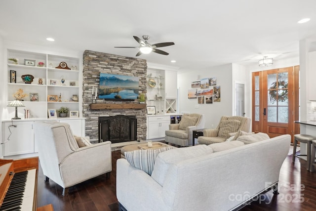 living room featuring ceiling fan, dark hardwood / wood-style floors, and a fireplace