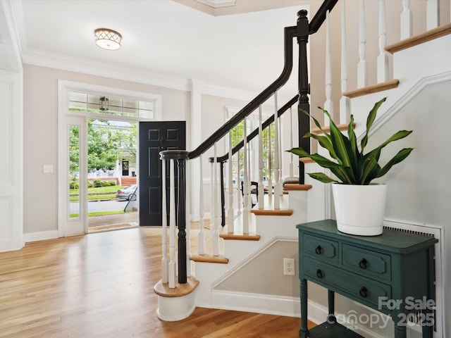 foyer with ornamental molding and light hardwood / wood-style floors