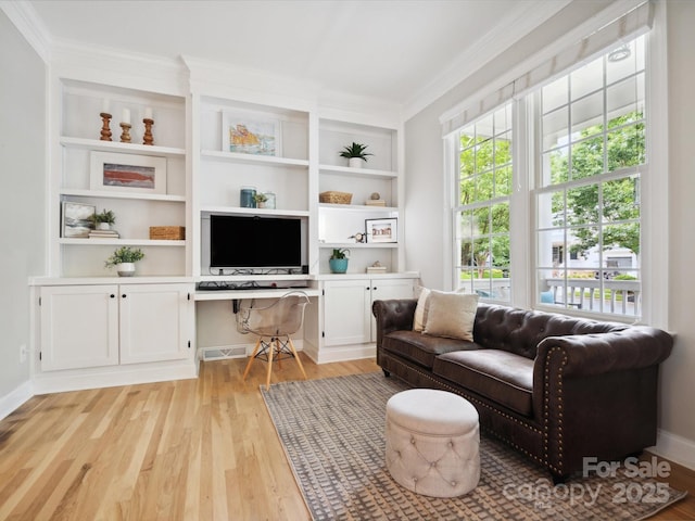 living room featuring built in desk, crown molding, and light hardwood / wood-style flooring