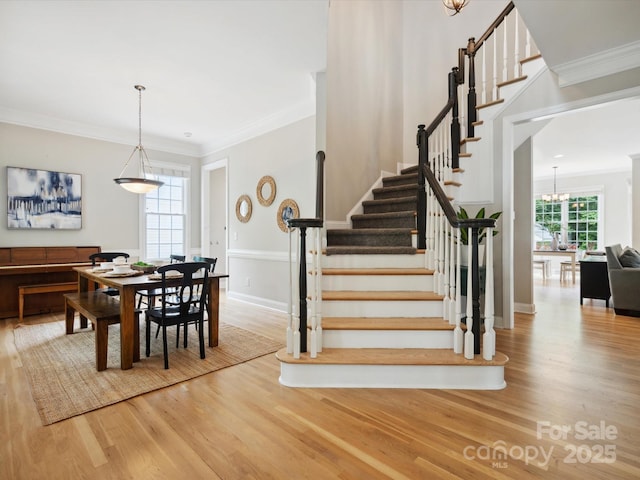 stairway featuring hardwood / wood-style flooring, crown molding, and a notable chandelier