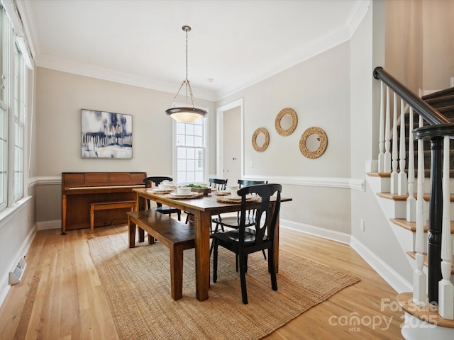 dining room featuring light wood-type flooring and crown molding