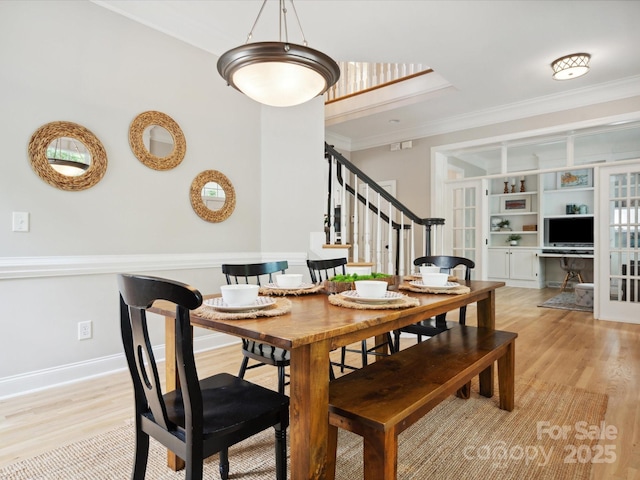 dining space featuring light hardwood / wood-style floors, built in features, and crown molding