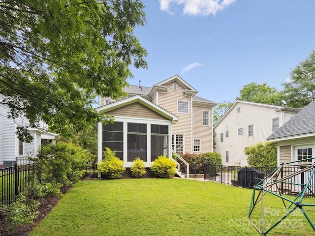 rear view of house featuring a playground, a sunroom, and a yard