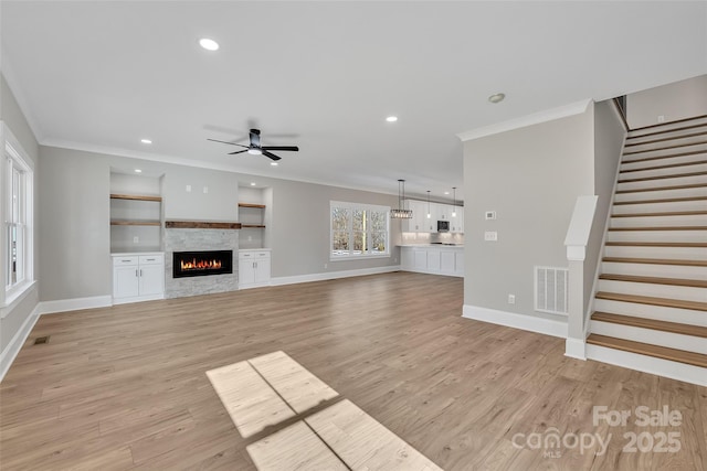 unfurnished living room with ceiling fan, crown molding, light hardwood / wood-style floors, and built in shelves