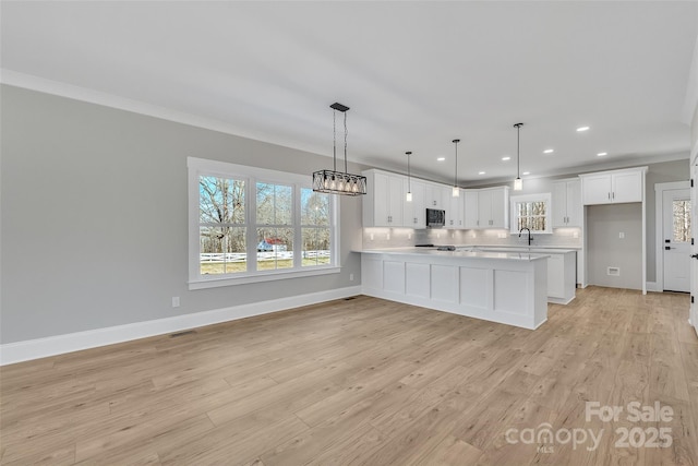 kitchen featuring sink, pendant lighting, white cabinets, and light wood-type flooring