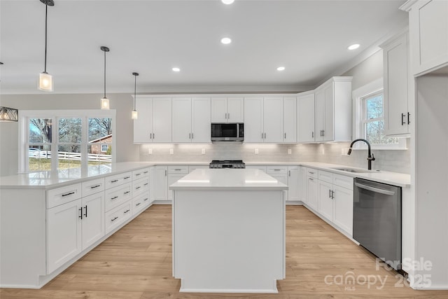 kitchen with stainless steel appliances, decorative light fixtures, a kitchen island, white cabinets, and sink