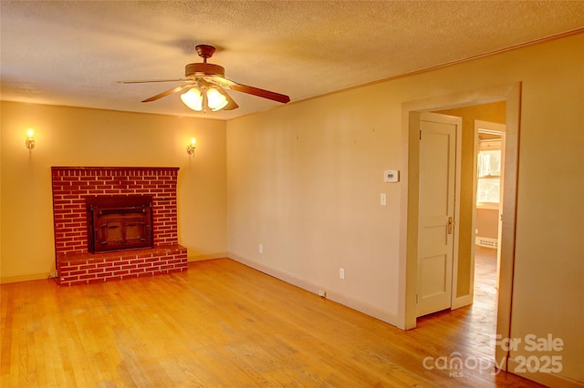 unfurnished living room featuring a brick fireplace, a textured ceiling, ceiling fan, and hardwood / wood-style floors