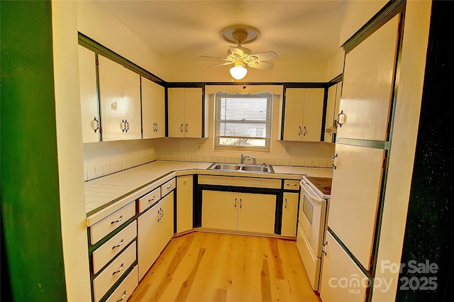 kitchen featuring sink, white cabinets, light wood-type flooring, and white electric range oven