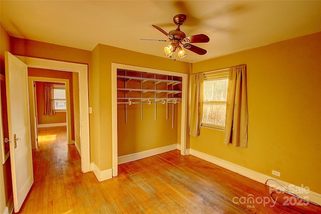 unfurnished bedroom with light wood-type flooring, ceiling fan, and a closet