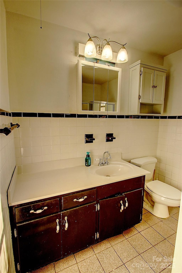 bathroom featuring toilet, vanity, and tile walls