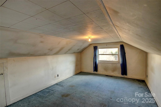 bonus room with lofted ceiling and light carpet