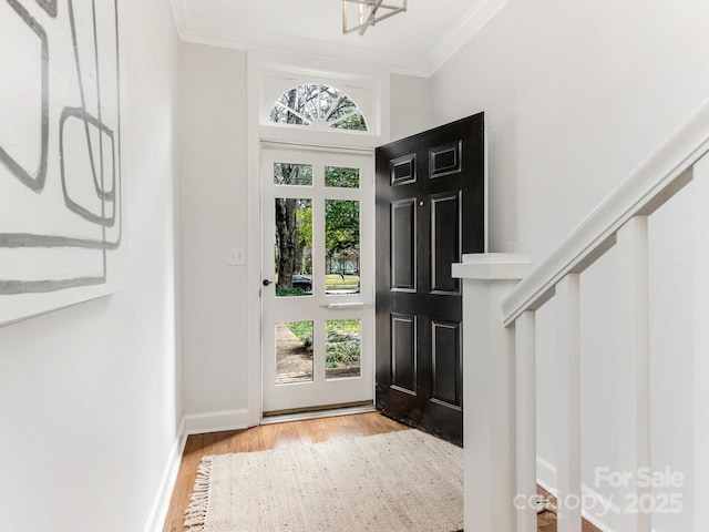 entryway with ornamental molding and light hardwood / wood-style flooring